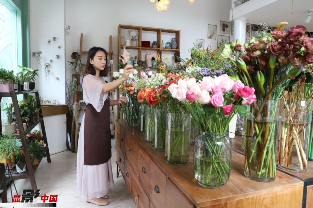 王黎媛是一名河南姑娘，在昆明念完大學(xué)后，就再也舍不下春城的藍(lán)天陽光、青山碧水，更舍不下這里的四時繁花，于是就干脆留了下來，成了一名媒體人。2017年的時候又毅然辭去工作，創(chuàng)業(yè)開起了花店，成了都市里的一名“花房姑娘”。圖為王黎媛在自己的花店中整理鮮花。新華網(wǎng) 周亞平/攝 念新洪/文